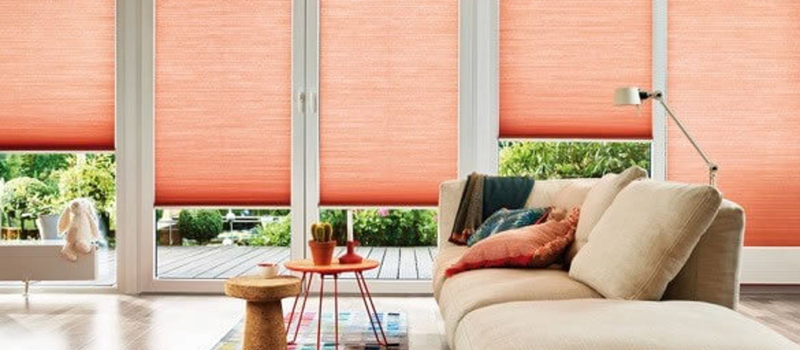 Colourful living space with large windows fitted with coral Duette blinds to keep the heat out