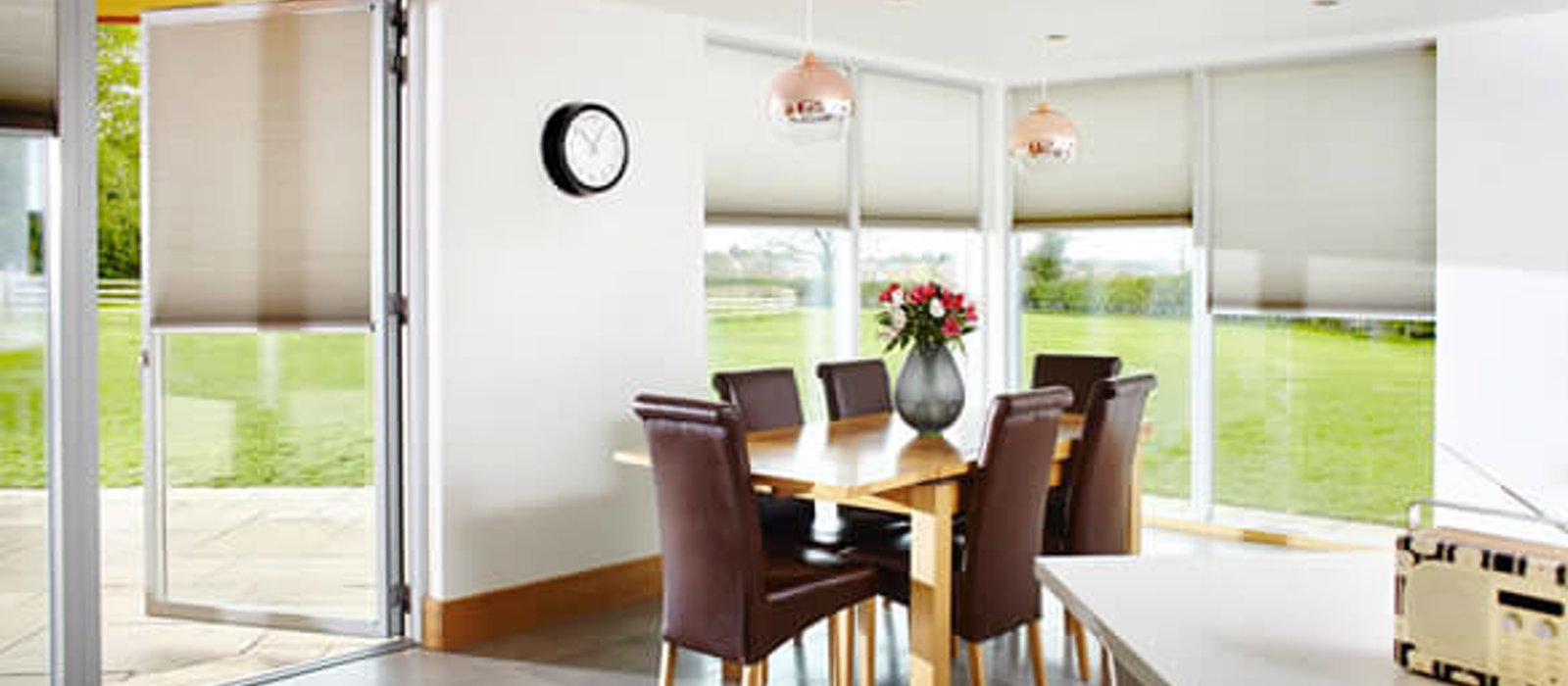 Dining area with large windows looking out to the garden fitted with Duette energy saving blinds